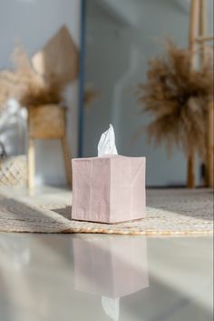 a tissue box sitting on the floor in front of a chair and table with a mirror behind it