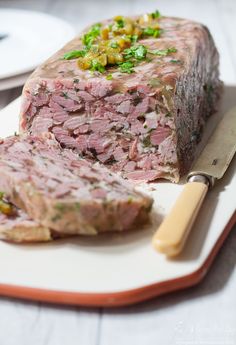 a piece of meat sitting on top of a cutting board next to a knife and fork