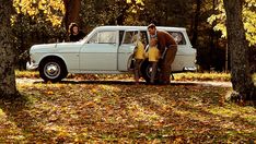 a man and two children standing in front of a white car