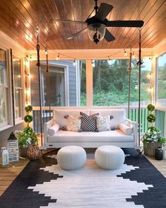 a porch with a swing bed, rug and pillows on the floor next to it