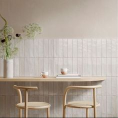 two wooden chairs sitting next to each other in front of a table with flowers on it