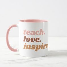 a pink and white coffee mug with the words teach love inspire written in orange on it