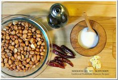 a wooden cutting board topped with a bowl of beans and other food items next to a blender