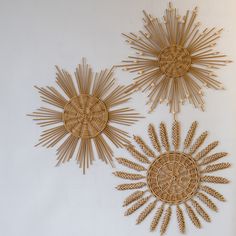 three woven sunbursts are hanging on the wall in front of a white wall