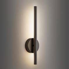 a wall mounted light on the side of a gray wall with a black pole attached to it