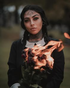 a woman with tattoos holding a bouquet of flowers in her hands and looking at the camera