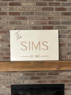 there is a sign that says the sims on top of a brick wall above a fireplace