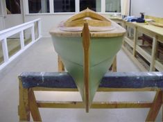 a green boat sitting on top of a wooden bench in a room filled with shelves