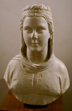 a statue of a woman's head with a crown on her head, sitting on top of a wooden table