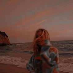 a woman standing on top of a beach next to the ocean