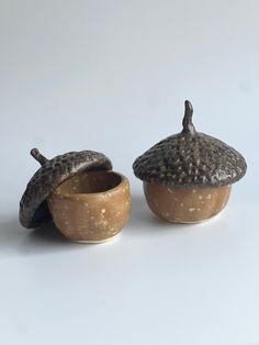 two small clay pots with lids on them sitting next to each other in front of a white background