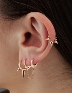 a woman's ear with three spikes and chains