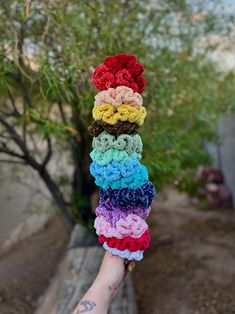 a person's hand holding up a stack of crochet flowers