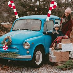 a woman standing next to a blue car with candy canes sticking out of it