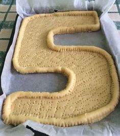 an uncooked cookie shaped like the letter s on top of baking paper in a pan