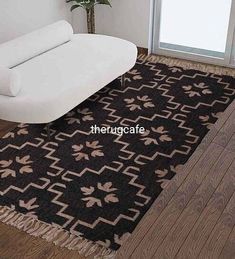 a white couch sitting on top of a hard wood floor next to a rug covered in black and brown designs