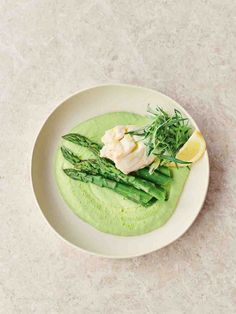 a white plate topped with asparagus and green sauce