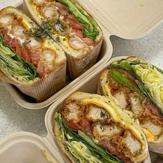 three takeout containers with sandwiches in them sitting on a counter top next to each other