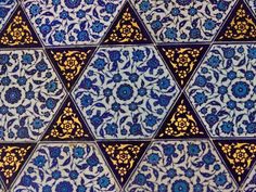 an intricate blue and yellow tile pattern with flowers on the bottom, surrounded by smaller hexagonal tiles