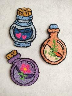 three embroidered patches depicting vases and flowers