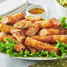 a white plate topped with chicken wings covered in lettuce next to a bowl of dipping sauce