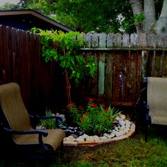 a chair sitting in the middle of a garden area next to a tree and fence