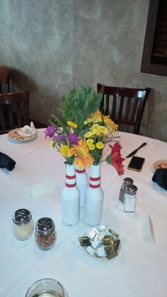 the table is set with flowers in vases and salt and pepper shakers on it