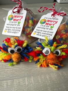 two small stuffed animals sitting next to each other on top of a wooden table with tags hanging from them