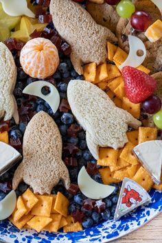 a blue and white plate topped with cheese, crackers, fruit and other snacks