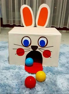 a cardboard box with an image of a bunny's face on it and balls in front of it