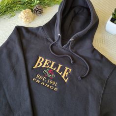 The Belle Embroidered Sweater brings a touch of Disney magic to your casual wardrobe. This unisex Hoodie features the iconic name 'Belle' embroidered in golden thread, accompanied by a detailed rose design. The embroidery provides a subtle nod to the beloved Beauty and the Beast character while maintaining a versatile, wearable look.

Offered in a range of colors, this sweater allows you to incorporate the Disney aesthetic into your everyday style. The golden embroidery adds a hint of elegance without being overstated. Whether you're a longtime Disney fan or simply appreciate tasteful designs, this piece makes a stylish statement.

#Beauty&theBeast #BeautyandtheBeast #Belle #DisneyPrincess #DisneySweater #BelleSweater #BelleHoodie #BeautyandtheBeastHoodie Golden Embroidery, Golden Thread, Belle Disney, Disney Sweaters, Disney Aesthetic, Embroidered Crewneck, Disney Fan, Embroidered Sweater, Embroidered Hoodie