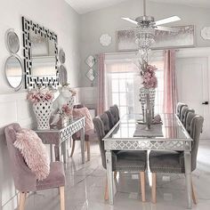 the dining room is decorated in white and pink colors with mirrors on the wall above it