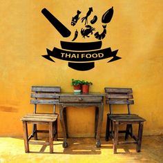 two wooden chairs sitting next to a table with a sign on it that says thai food