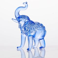 an elephant glass figurine is shown on a reflective surface with its trunk in the air