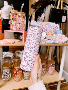 a person holding up a water bottle in front of a shelf with other items on it