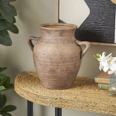 a brown vase sitting on top of a table next to a book and planter