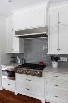 a kitchen with white cabinets and stainless steel stove top oven in the center of the room