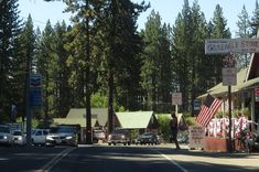 cars are parked on the side of the road in front of small shops and businesses