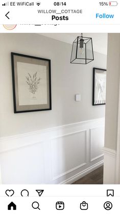 a white room with two pictures hanging on the wall and a light fixture above it