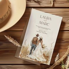 a wedding book on a wooden table next to a cowboy hat and straws,