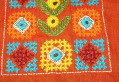 an orange sweater with flowers and leaves on the front, is shown in this close up photo