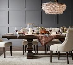 a dining room table is set with white chairs and a chandelier hanging from the ceiling