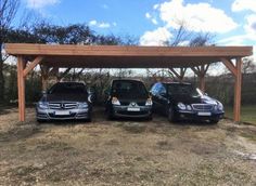 three cars are parked under a wooden structure