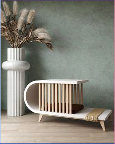 a white vase with dried plants in it next to a modern credet table