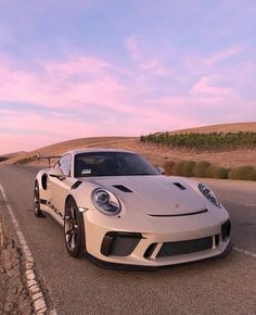 a white sports car driving down the road