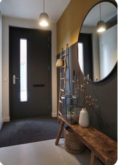 a wooden bench sitting in front of a mirror next to a wall mounted light fixture