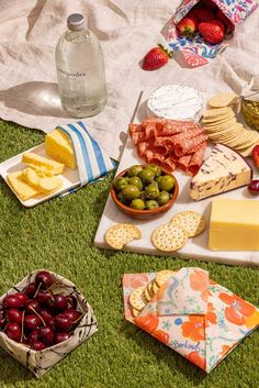 an assortment of cheeses, fruit and crackers on a picnic blanket