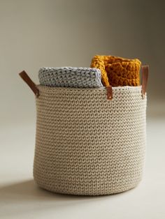 a knitted basket with two handles and leather handles