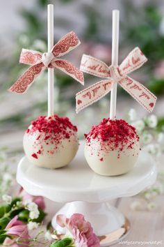 two white cake pops with red sprinkles on them sitting on a plate