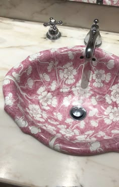 a pink flowered sink with chrome faucet and soap dispenser